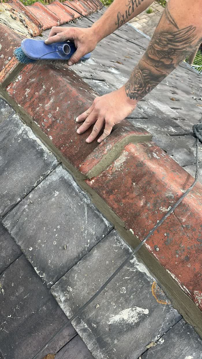 Ridge repair being finished by hand on a tiled roof